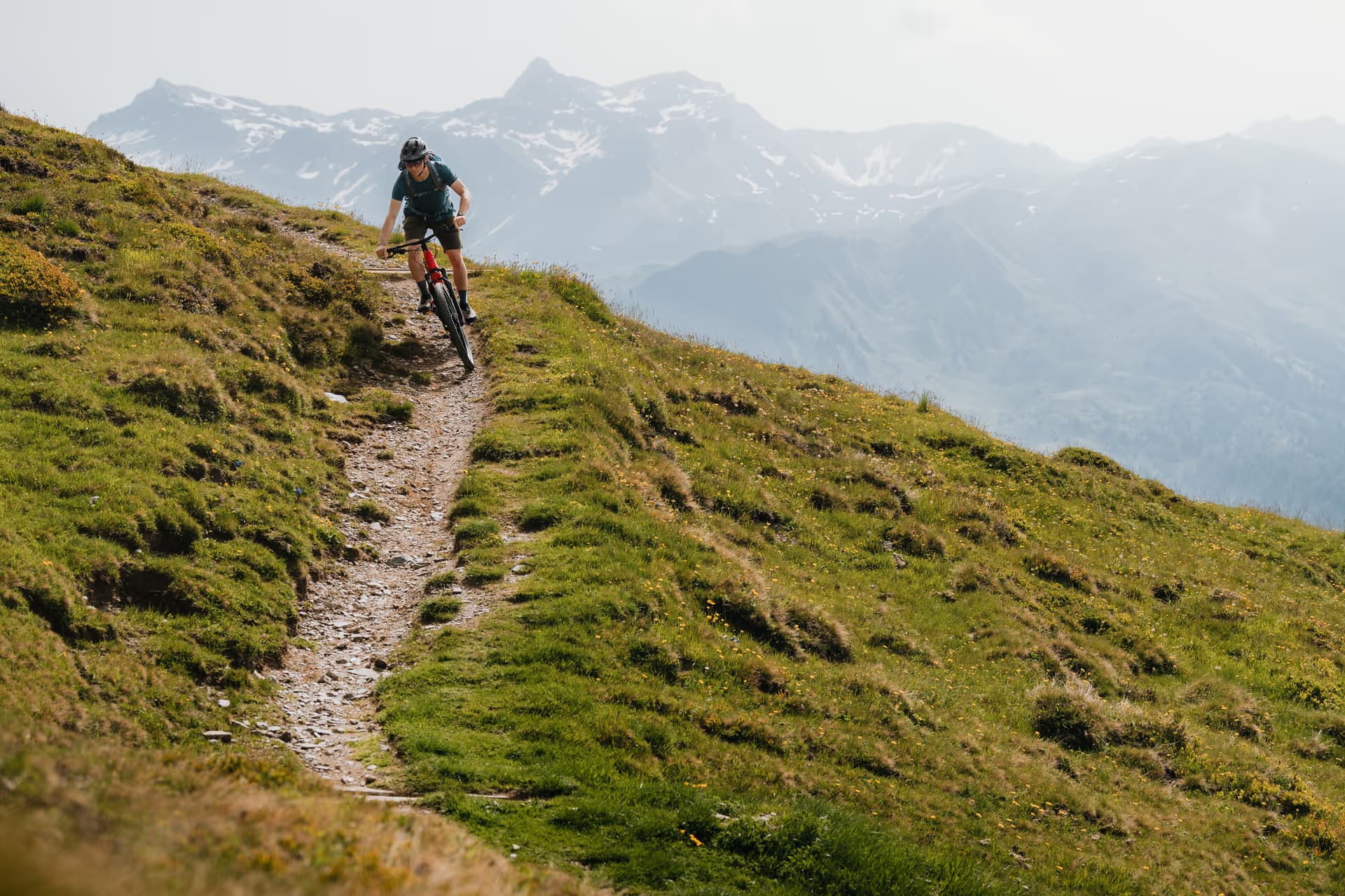 Mountainbiker auf einem Singletrail am Grenzkamm mit Blick auf die Gipfel zwischen Tirol und Südtirol