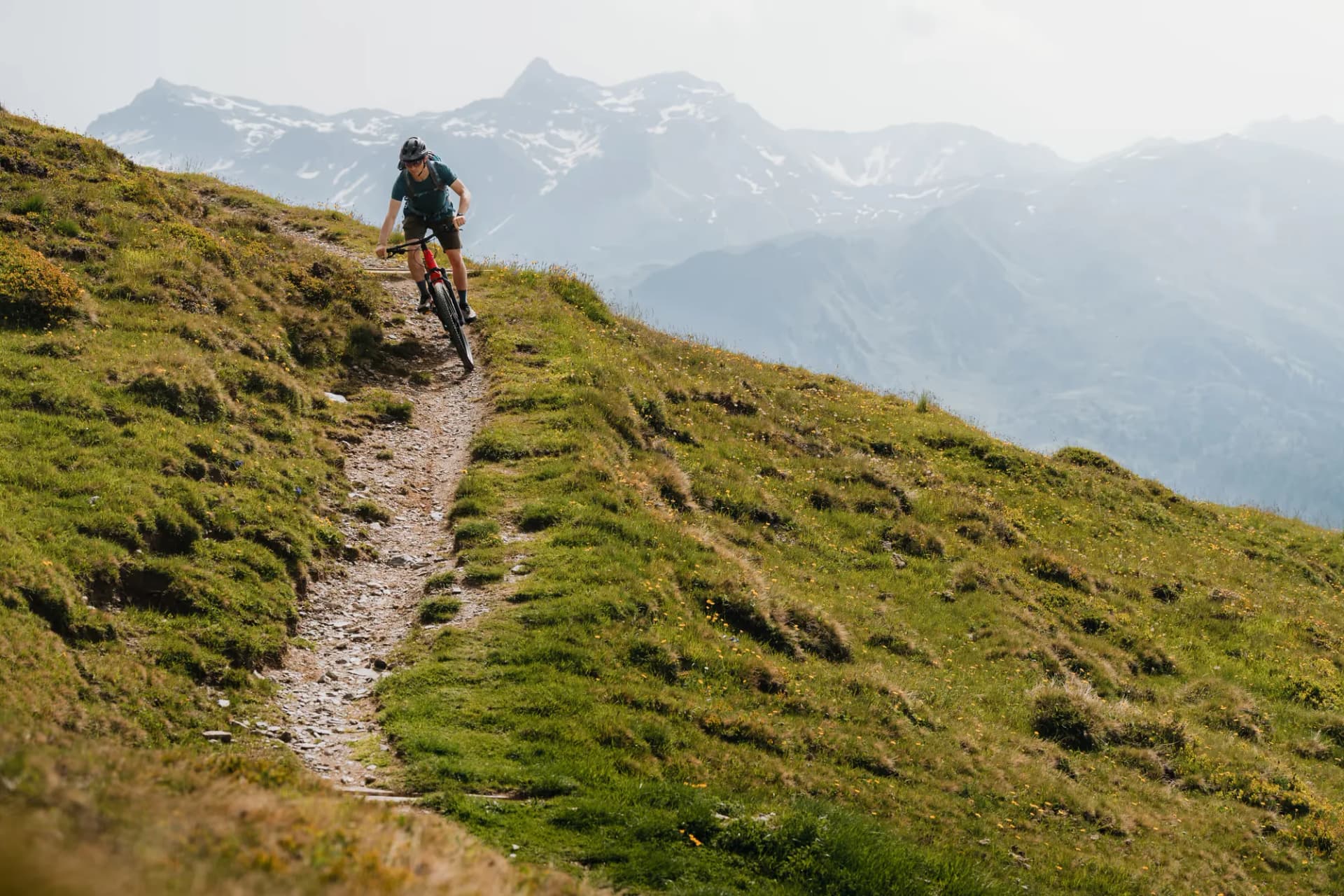 Mountainbiker auf einem Singletrail am Grenzkamm mit Blick auf die Gipfel zwischen Tirol und Südtirol
