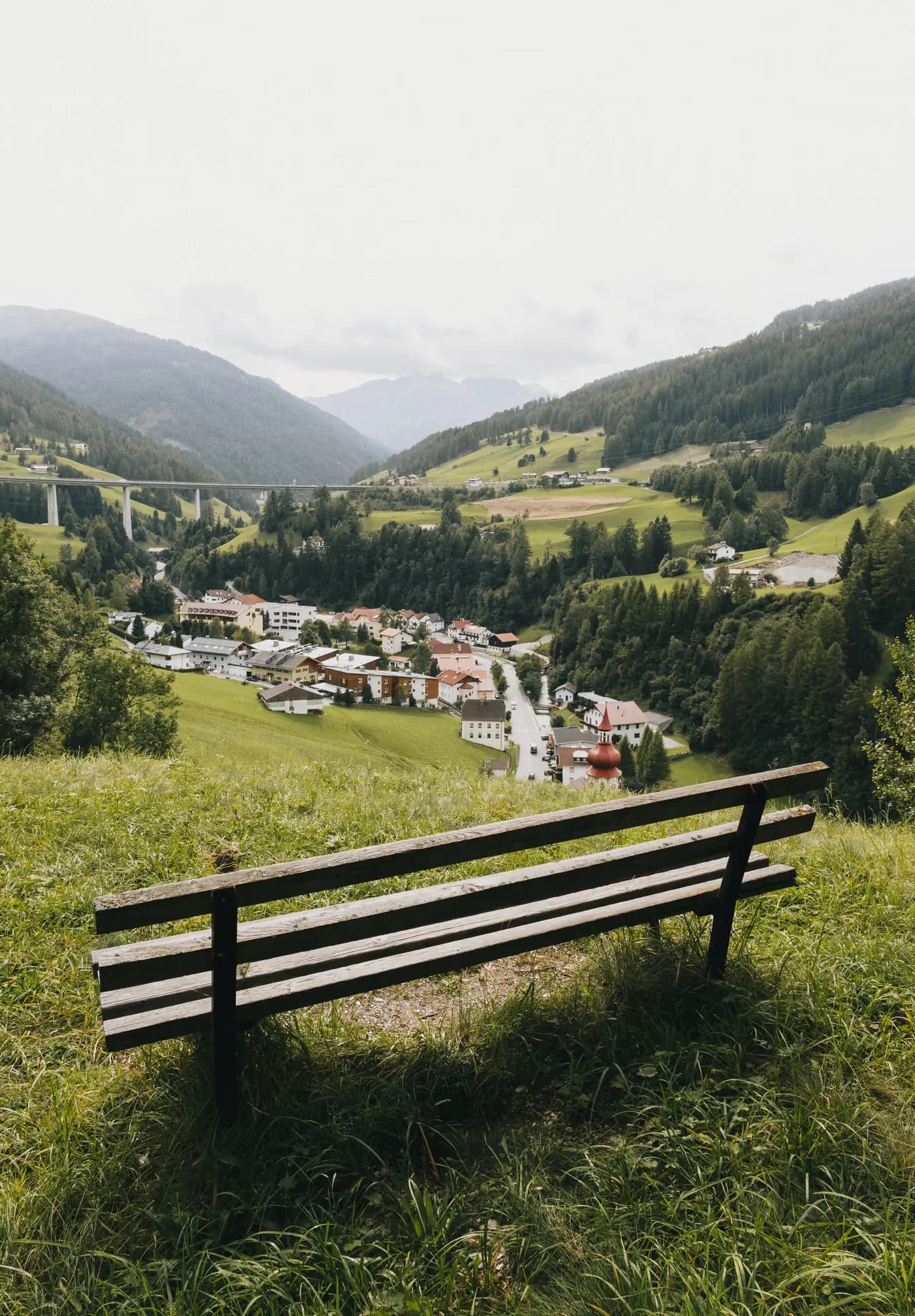 Holzbank auf einer Bergwiese mit Blick über Gries am Brenner und das Viadukt der Brennerautobahn