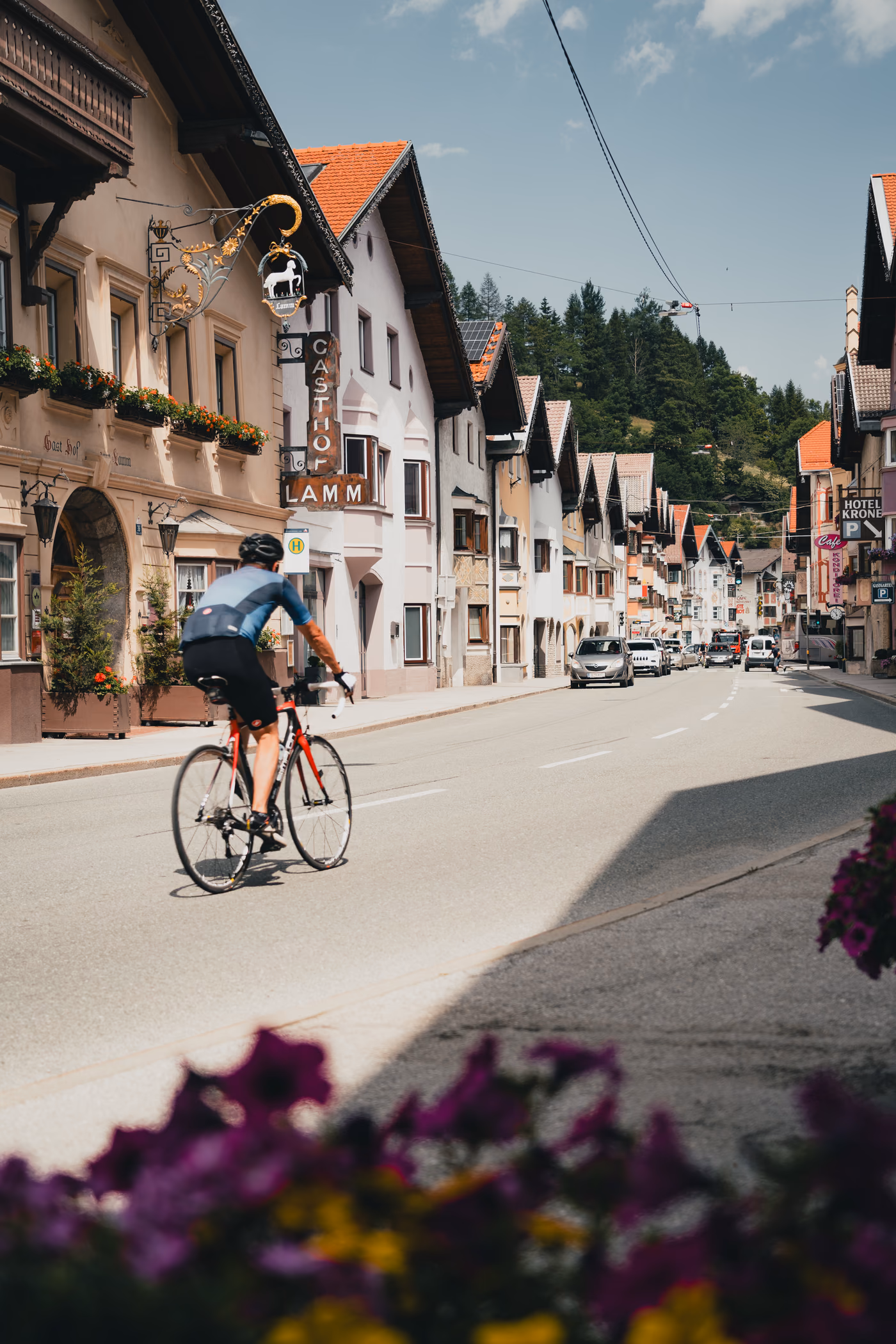 Auf dem Rennrad durch die historische Dorfstraße von Matrei am Brenner, vorbei am Gasthof Lamm mit schmiedeeisernem Zunftschild