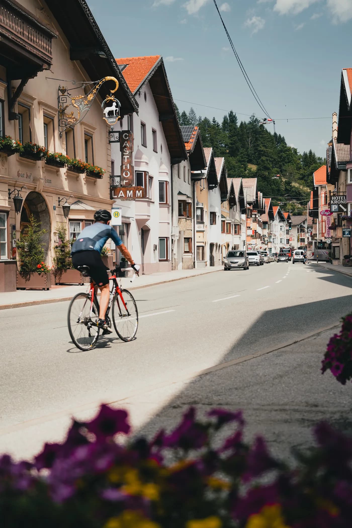 Auf dem Rennrad durch die historische Dorfstraße von Matrei am Brenner, vorbei am Gasthof Lamm mit schmiedeeisernem Zunftschild