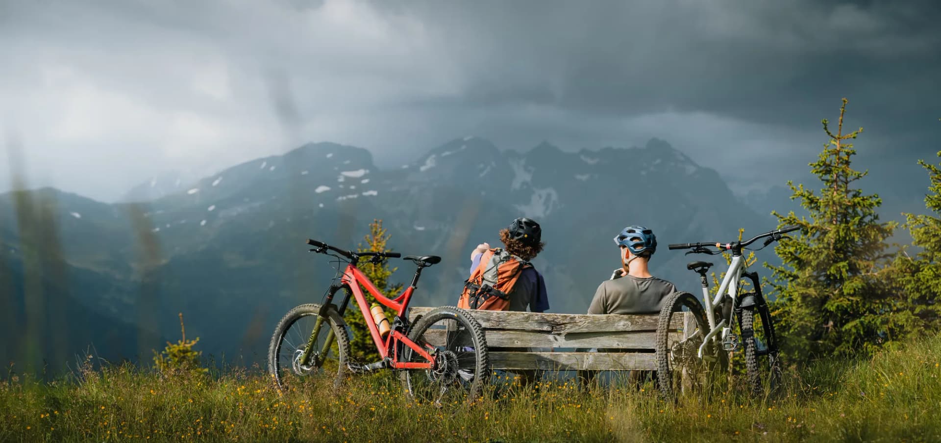 Mountainbiker rasten auf einer Bank über Trins mit Blick auf die Wipptaler Berge