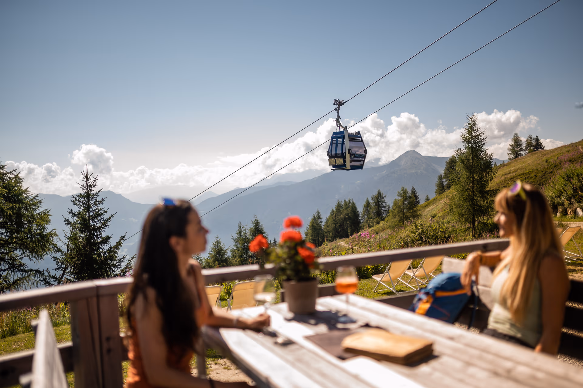 Sonnige Almterrasse am Rosskopf über Sterzing mit Gondelbahn und Blick auf die Südtiroler Berge