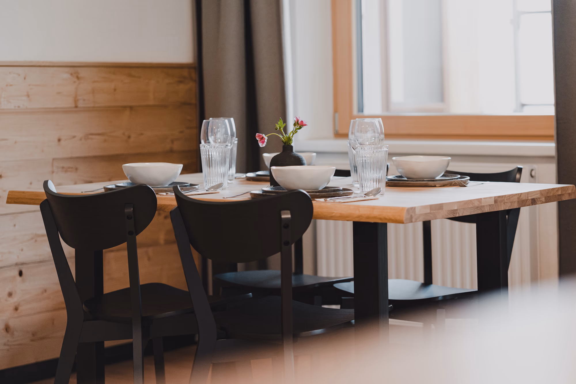 Apartment Auszeit Stoacherhof – gedeckter Esstisch aus Massivholz mit schwarzen Stühlen am Fenster | Ferienwohnung Wipptal Tirol