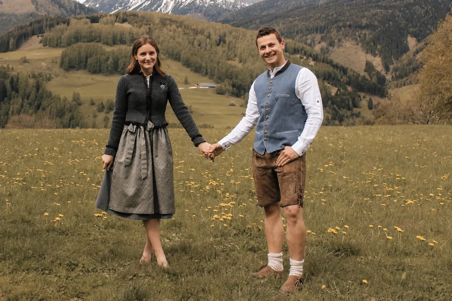 Julia und Wolfgang Strickner in Tracht auf der Bergwiese – Ihre Gastgeber am Stoacherhof